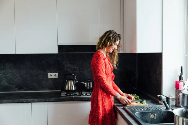Mooie vrouw huisvrouw bereidt een salade van groenten in de keuken — Stockfoto