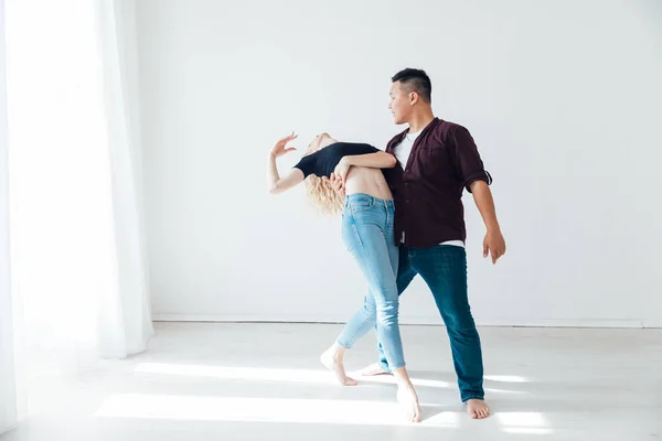 Um homem e uma mulher dança bachata música em um quarto branco — Fotografia de Stock