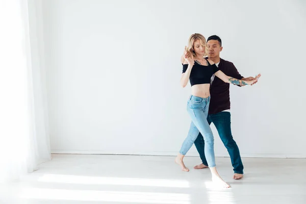 Een man en een vrouw dansen bachata muziek in een witte kamer — Stockfoto