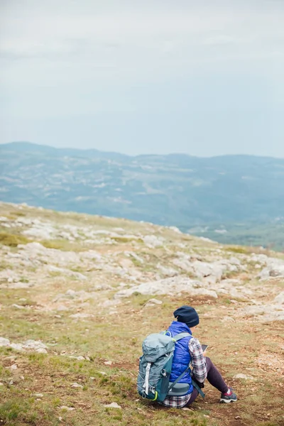 A woman looks at a smartphone on top of a mountain on a hiking trip — Stock Photo, Image