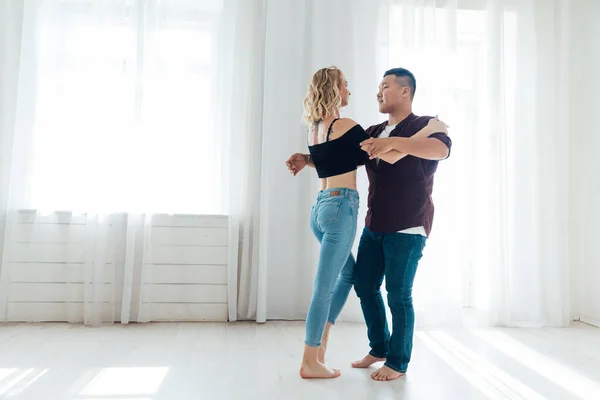 Mooie man en vrouw dansen samen op muziek in een witte kamer — Stockfoto