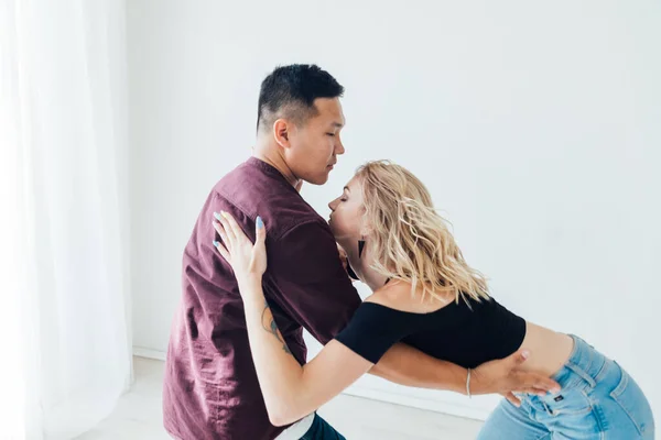 Beautiful man and woman dancing together to music in a white room — Stock Photo, Image