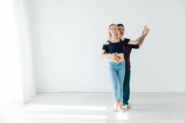 Belo homem e mulher dançando juntos para a música em uma sala branca — Fotografia de Stock