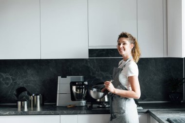 Güzel kadın ev hanımı mutfakta lezzetli yemekler pişirir.