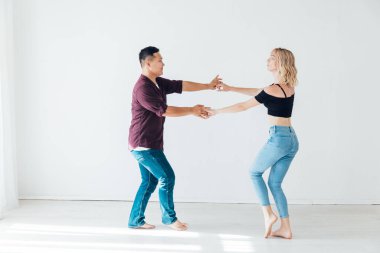 Bir erkek ve bir kadın beyaz bir odada bachata dansı yapıyorlar.