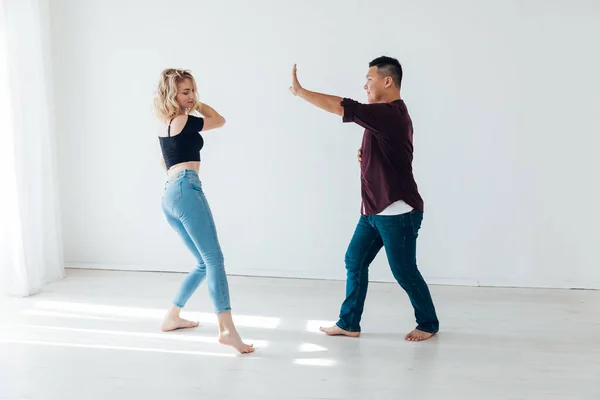 Een man en een vrouw dansen bachata muziek in een witte kamer — Stockfoto