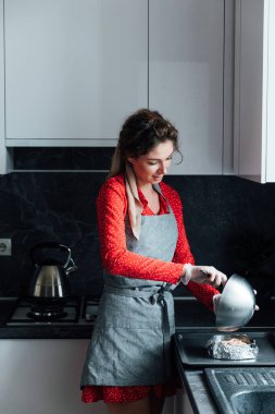 Kırmızı elbiseli kadın mutfaktaki tatlıları hazırlıyor.