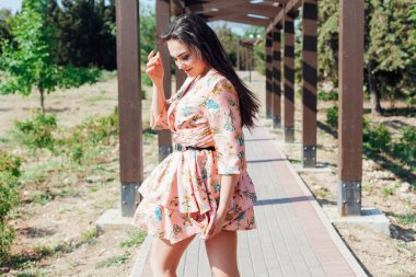 Güzel bir esmer kadın parkta poz veriyor.