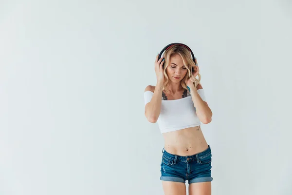 Mujer rubia bailando música en auriculares en el entrenamiento —  Fotos de Stock