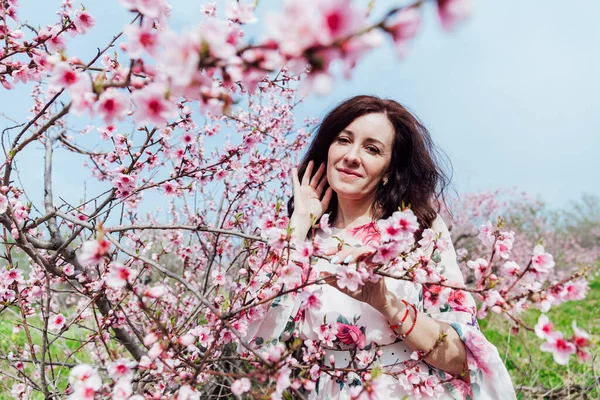 Bela mulher em um vestido no jardim de árvores floridas na primavera — Fotografia de Stock