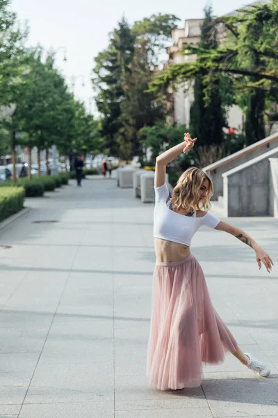 Krásná blondýnka tanec na hudbu na ulici sám — Stock fotografie