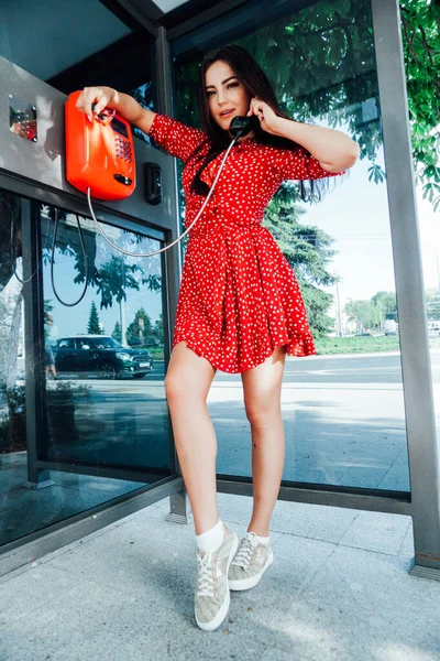 Porträt einer schönen brünetten Frau in einem roten Sommerkleid auf der Straße — Stockfoto