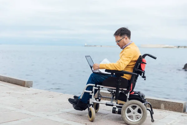 a man with disabilities in a wheelchair works on a computer on the Internet