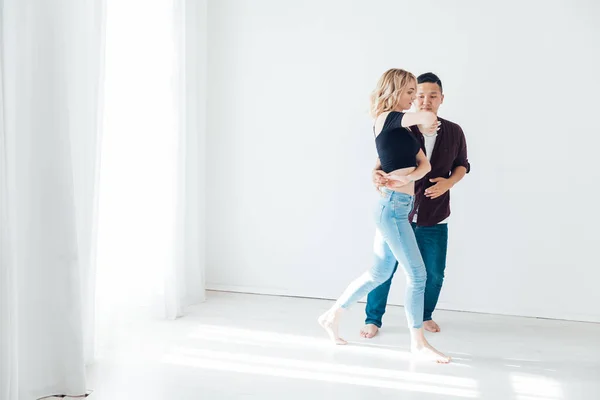 Belo homem e mulher dançando bachata para a música em uma sala branca — Fotografia de Stock
