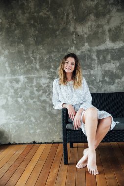 Gri arka planda, elbise giymiş bir kadın.