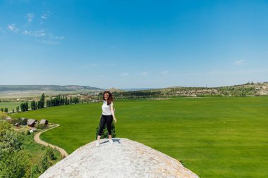 Güzel bir kadın bir uçurumun tepesindeki manzaraya bakar bir yolculukta