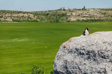 Güzel bir kadın bir uçurumun tepesindeki manzaraya bakar bir yolculukta