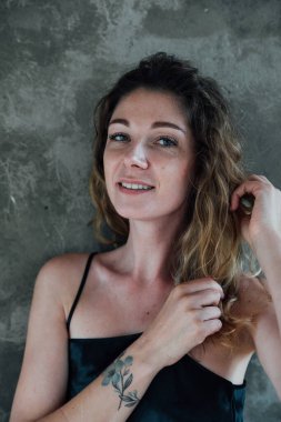 Gri arka planda, elbise giymiş bir kadın.