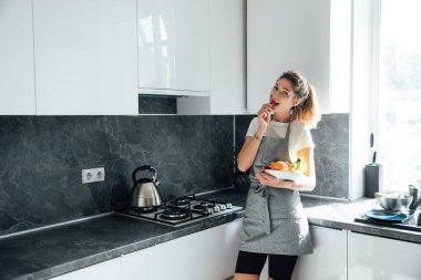 Güzel kadın ev hanımı mutfakta tatlı meyve yer.