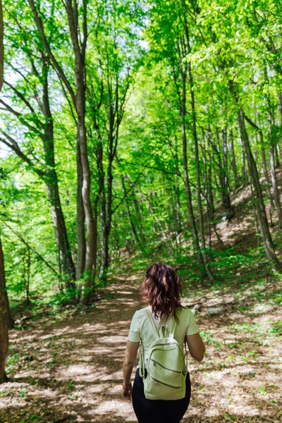 Mulher andando pela estrada em uma caminhada de viagem de floresta verde — Fotografia de Stock