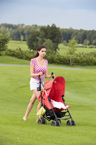 Glad ung mamma med bebis i barnvagn promenader — Stockfoto