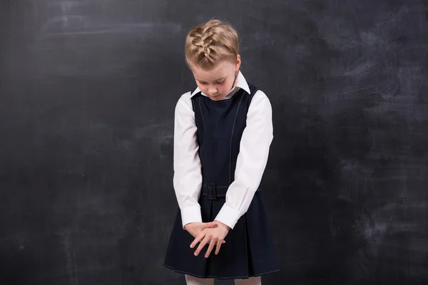 Triest weinig schoolmeisje in de buurt van blackboard — Stockfoto