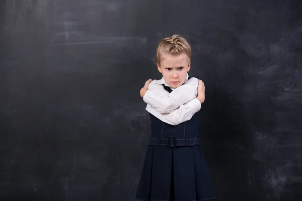 Schoolgirl leunend op haar voorhoofd tegen blackboard — Stockfoto