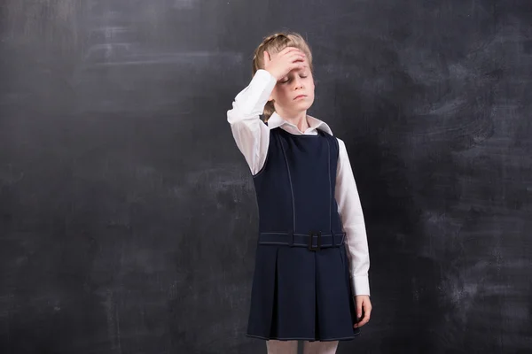 Schoolmeisje met hoofdpijn staat op het bord — Stockfoto