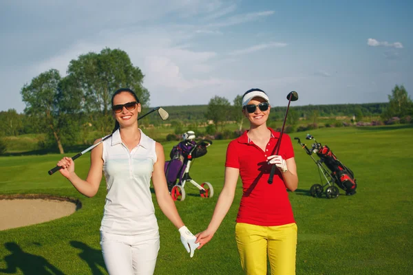 Dos mujeres guapas golfistas caminando en el campo de golf — Foto de Stock