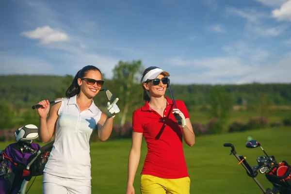 Dos mujeres guapas golfistas caminando en el campo de golf —  Fotos de Stock