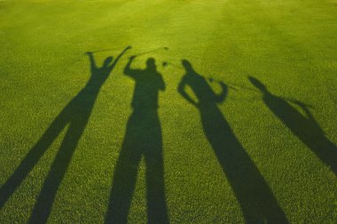 Dört golfçüler siluet çimenlerin üzerinde