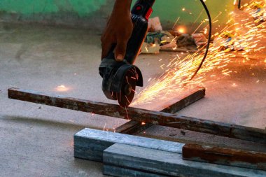 İnşaat alanında çeliği bir açı öğütücüyle kesen bir işçi
