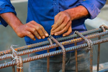 İnşaat işçisi çelik demiri bağlayıcı kabloyla bağlıyor, yakın çekim takviye işi.