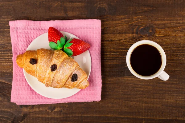 Färska franska croissant och jordgubb. kopp kaffe. träbord bakgrund. Ovanifrån — Stockfoto