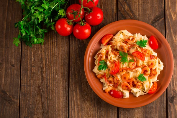 Fettuccine makarna karides domates ve otlar ile. ahşap arka plan