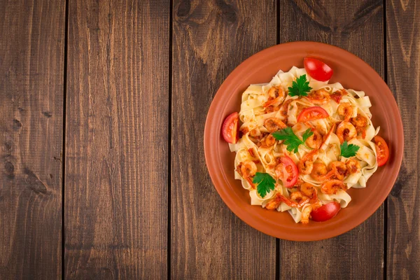 Fettuccine makarna karides domates ve otlar ile. ahşap arka plan