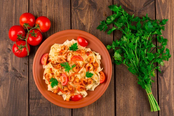 Fettuccine makarna karides domates ve otlar ile. ahşap arka plan