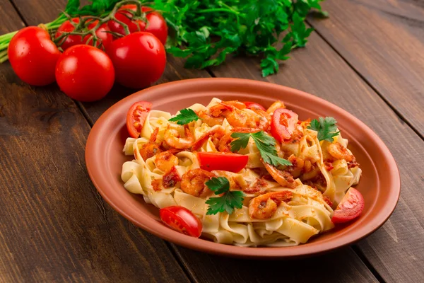 Fettuccine makarna karides domates ve otlar ile. ahşap arka plan