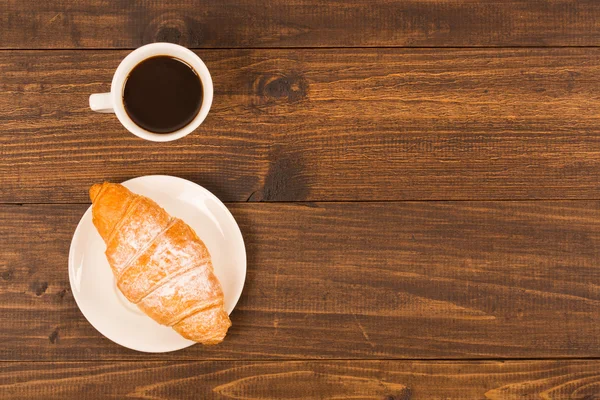 Kaffekopp med croissanter till frukost på ett mörka träbord, ovanifrån — Stockfoto