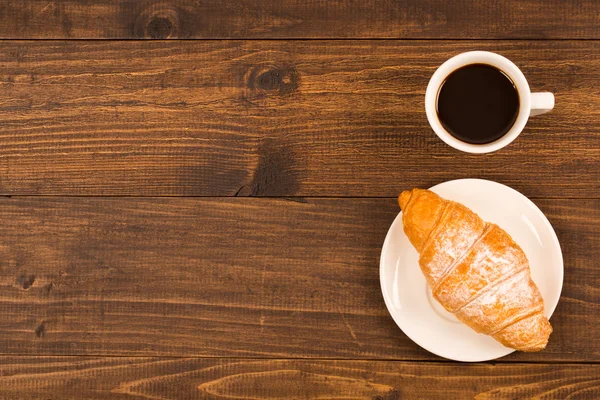 Kaffekopp med croissanter till frukost på ett mörka träbord, ovanifrån — Stockfoto