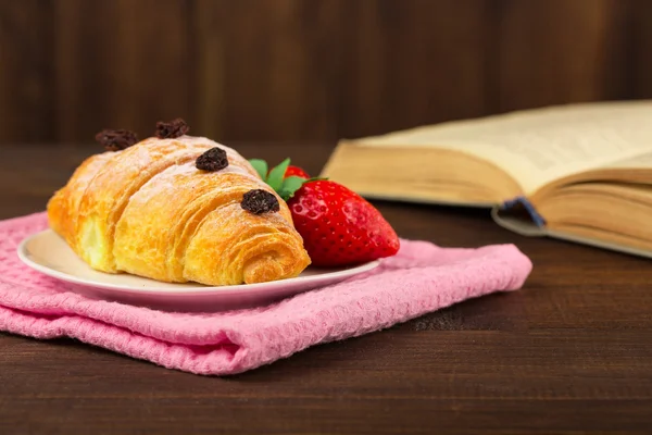 Croissant med bok i kafé — Stockfoto