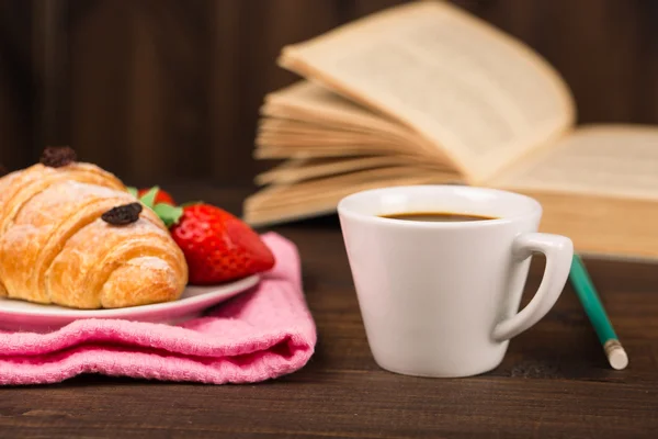 Kopp kaffe och en croissant och bok — Stockfoto