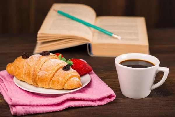 Kopp kaffe och en croissant och bok — Stockfoto