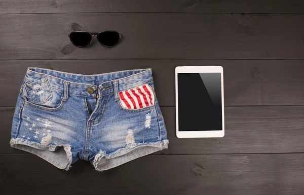 Acessórios femininos de verão: shorts, tablet, óculos de sol sobre fundo de madeira . — Fotografia de Stock