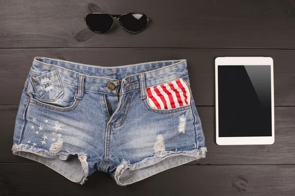 Acessórios femininos de verão: shorts, tablet, óculos de sol sobre fundo de madeira . — Fotografia de Stock