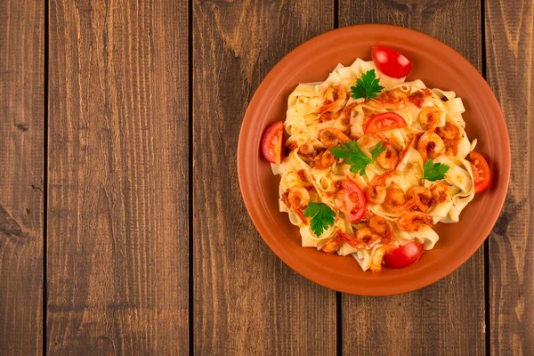 Fettuccine makarna karides domates ve otlar ile. ahşap arka plan. Üstten Görünüm