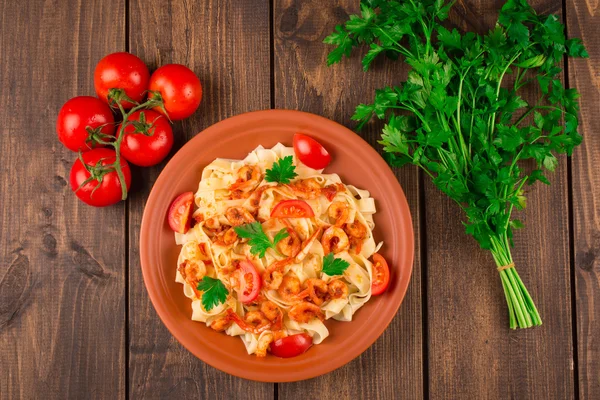 Fettuccine tészta garnélarák paradicsom és gyógynövények. fából készült háttér. Szemközti nézet — Stock Fotó