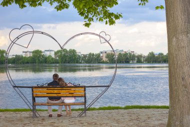 Büyük bir göl önünde bir bankta oturan çift