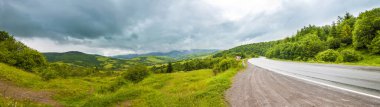 Yol dramatik gökyüzü ve ağır bulutlar panorama ile dağlarda