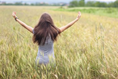 Buğday alan yükselterek uzun kahverengi saçlı ayakta olan kadın
